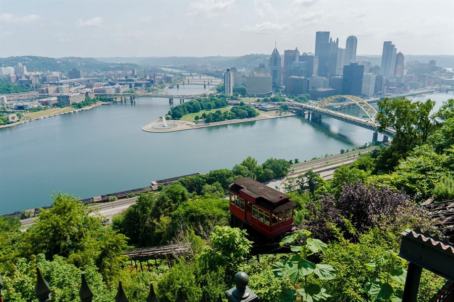 A red incline car on Mount Washington above the rivers and skyline of Pittsburgh