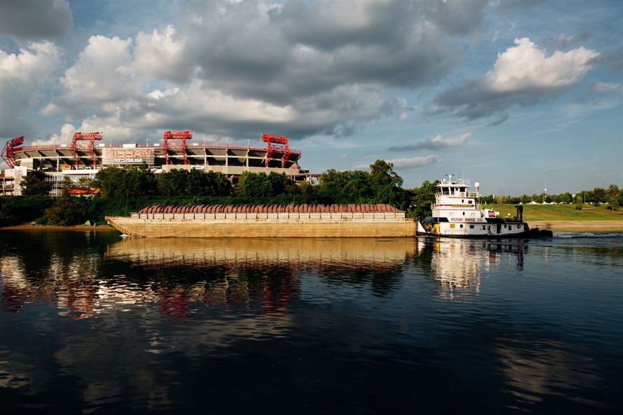 A towboat and barge passing the football stadium on the Cumberland River in Nashville