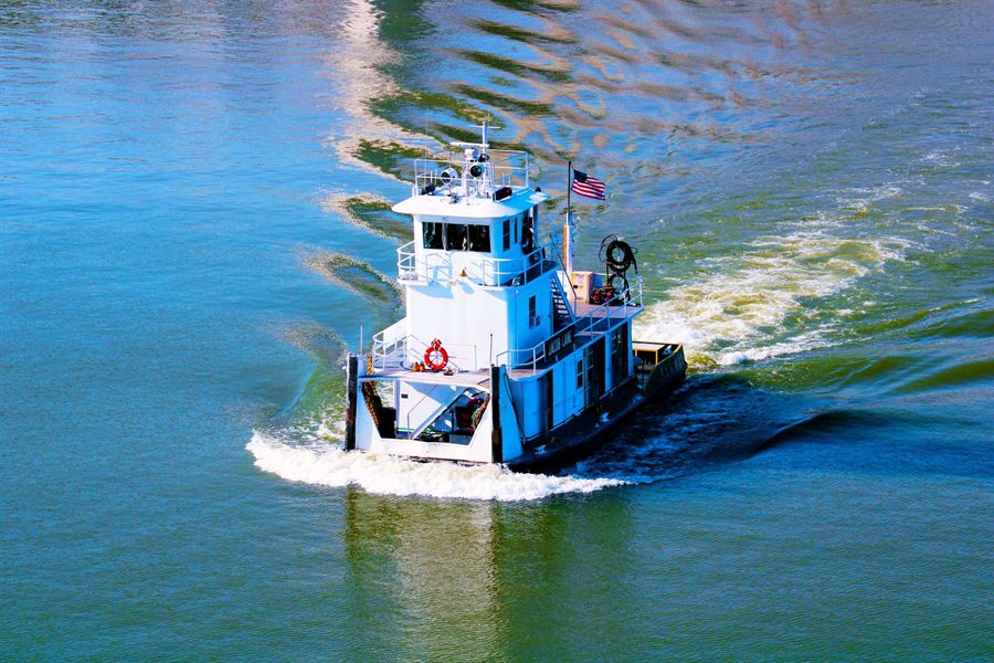 A blue towboat churning up the Ohio River at Louisville